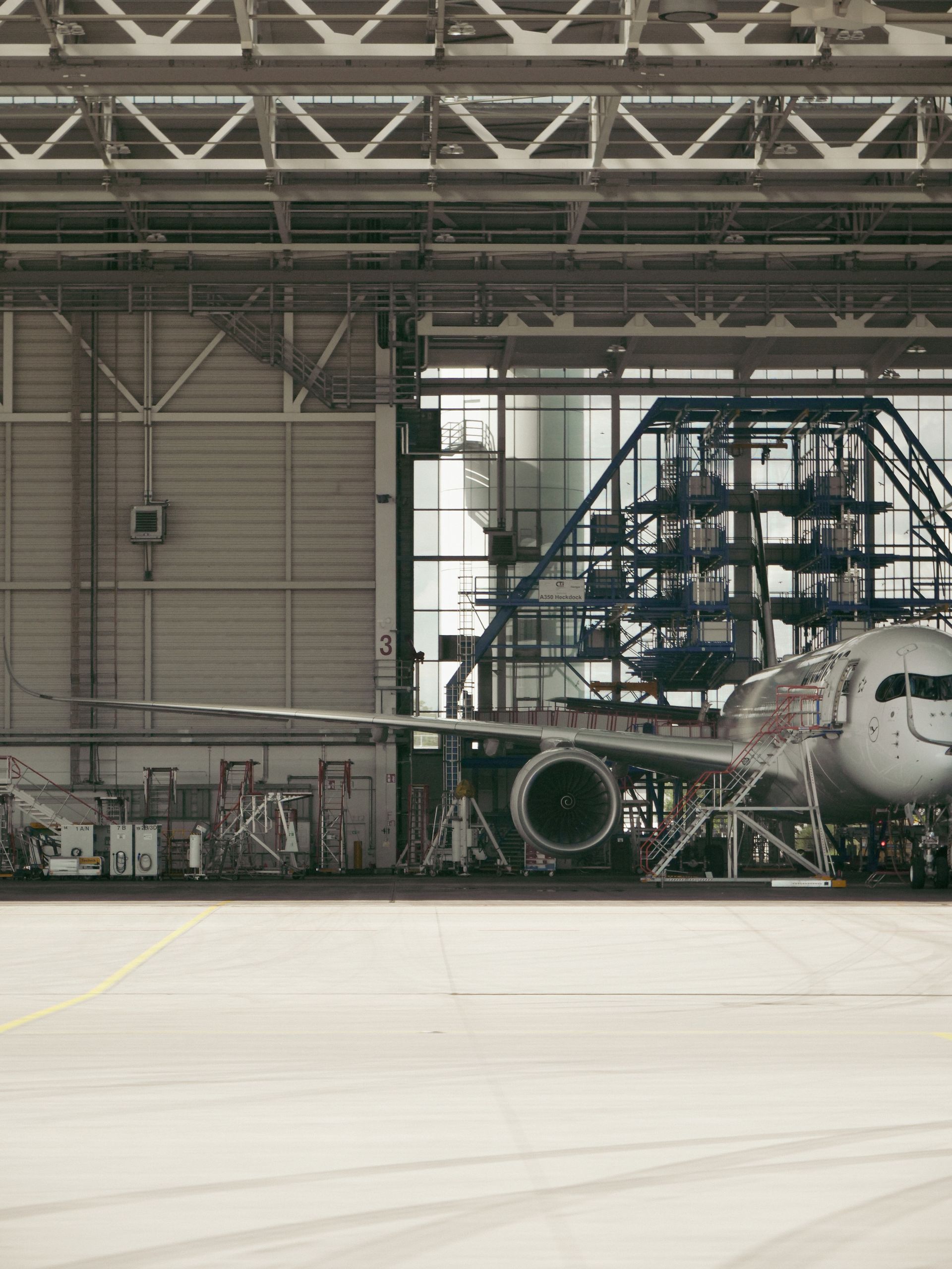 A commercial airliner inside a maintenance hangar with its engine cowlings open