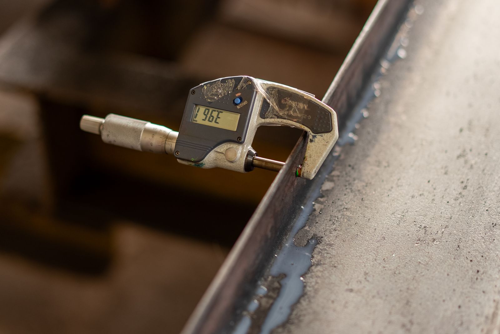 A digital caliper measures a metal part