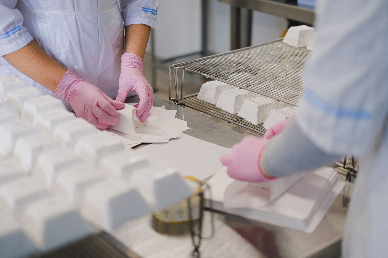 Workers wrap cheese blocks in a food plant