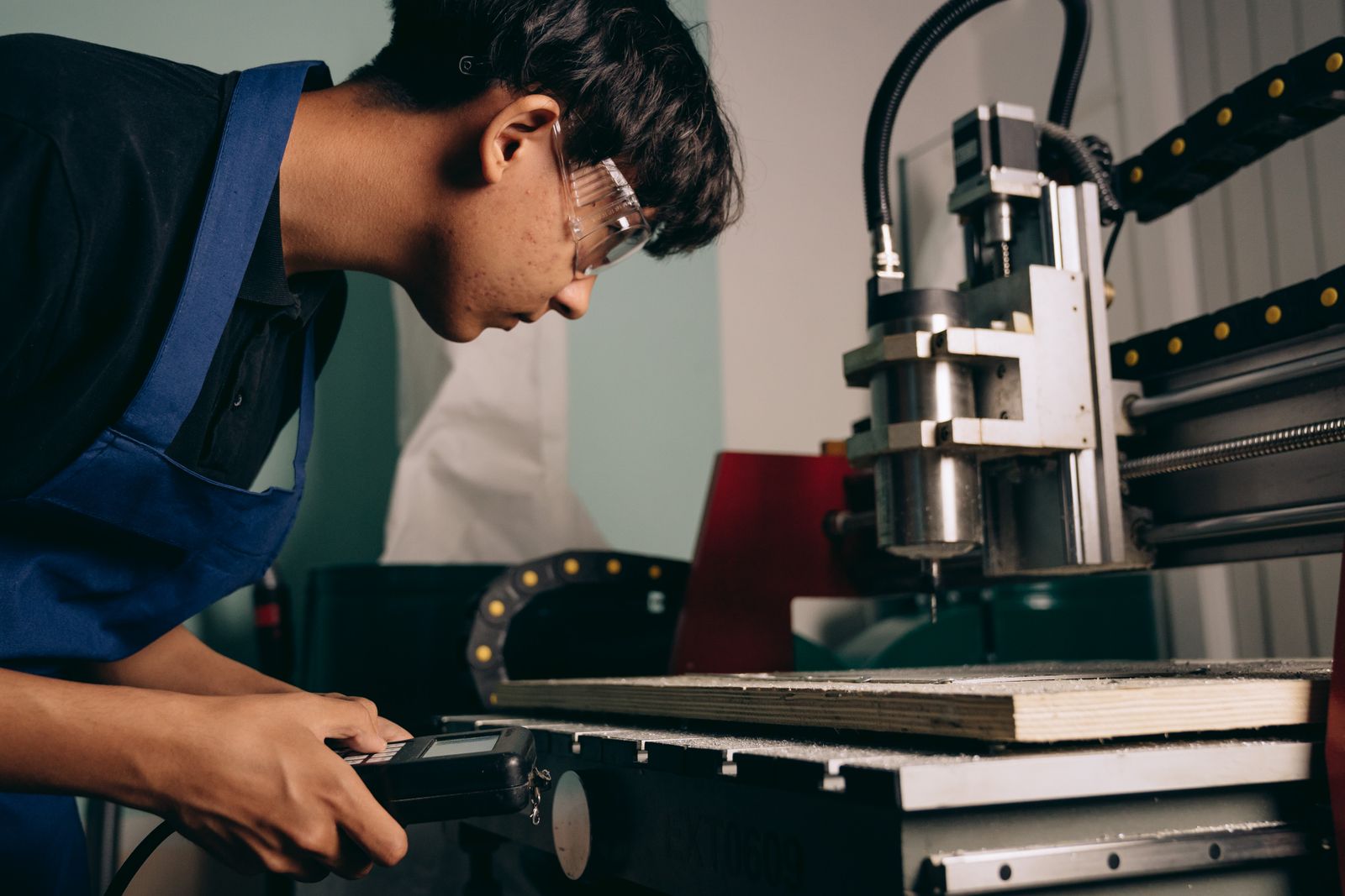 An operator in safety goggles runs a CNC machine