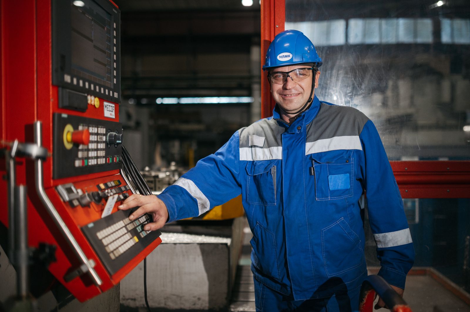 A machinist in safety gear at a CNC machine