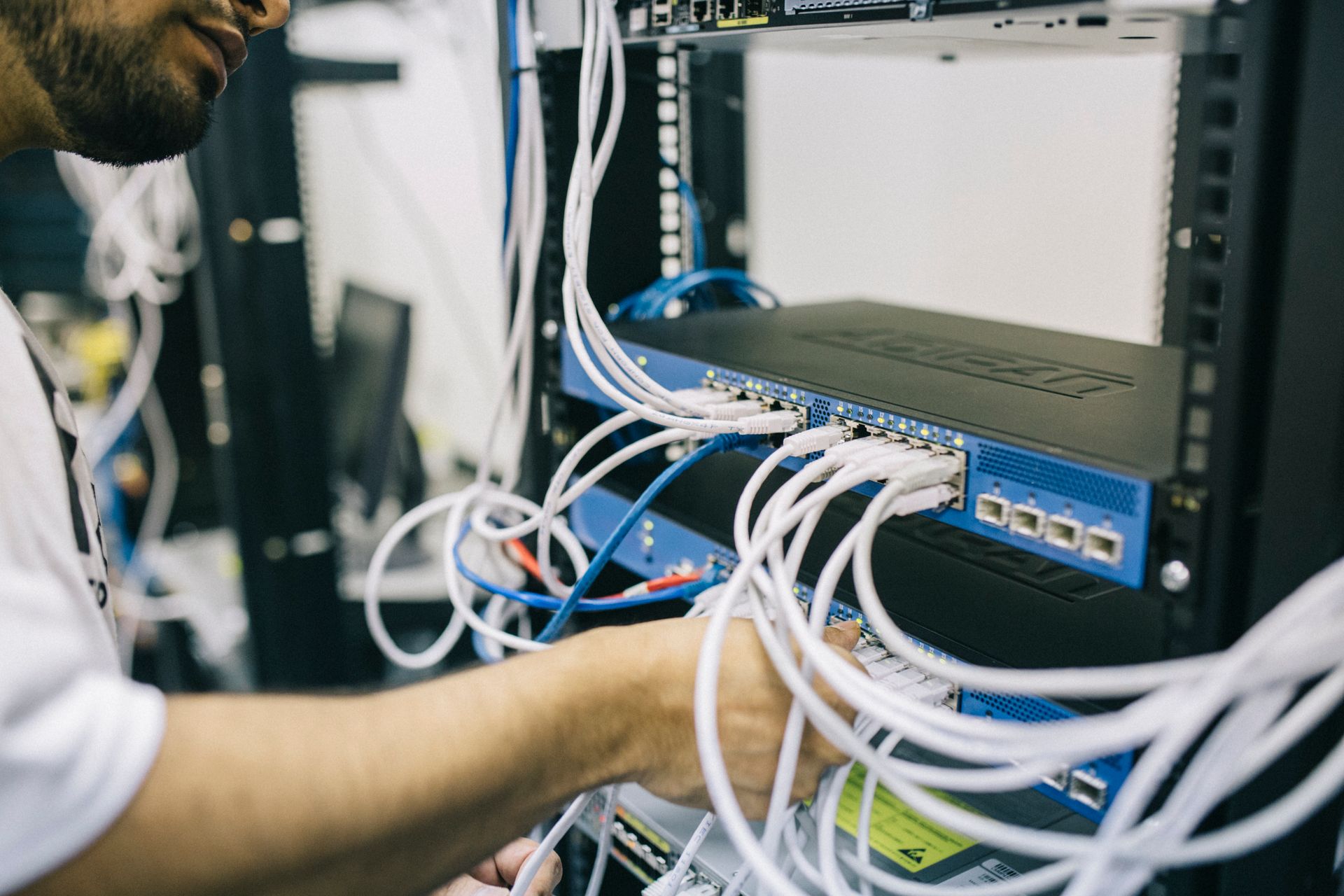 A technician connects network cables inside a server rack