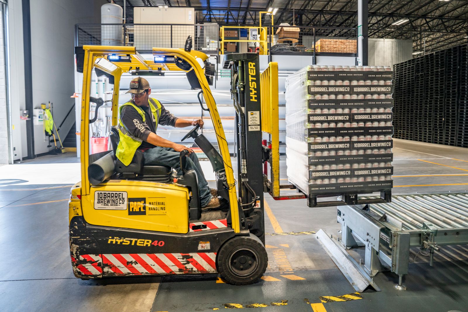 A warehouse worker moves crates with a forklift