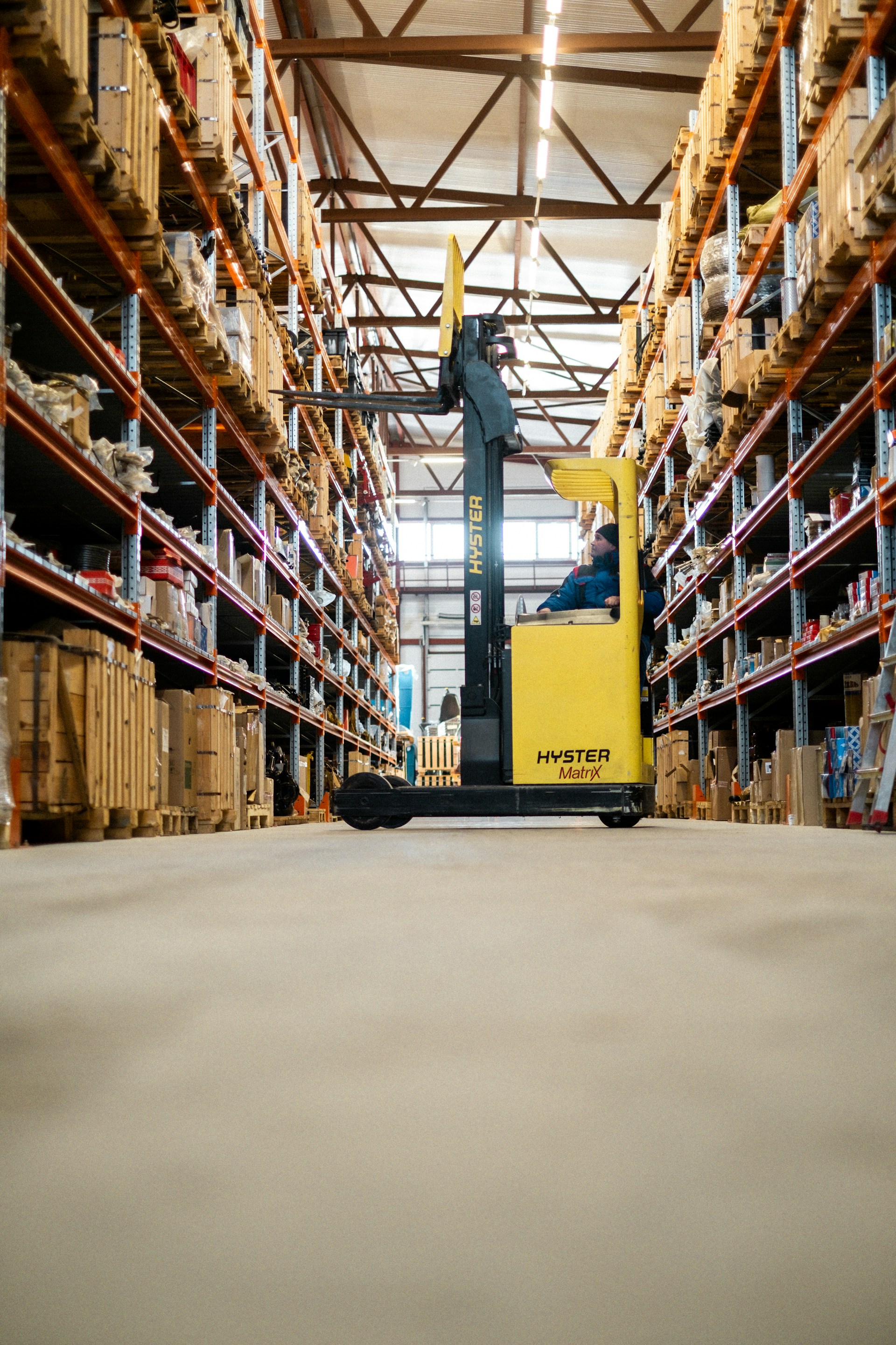 A reach truck operator moves stock in a racked warehouse aisle
