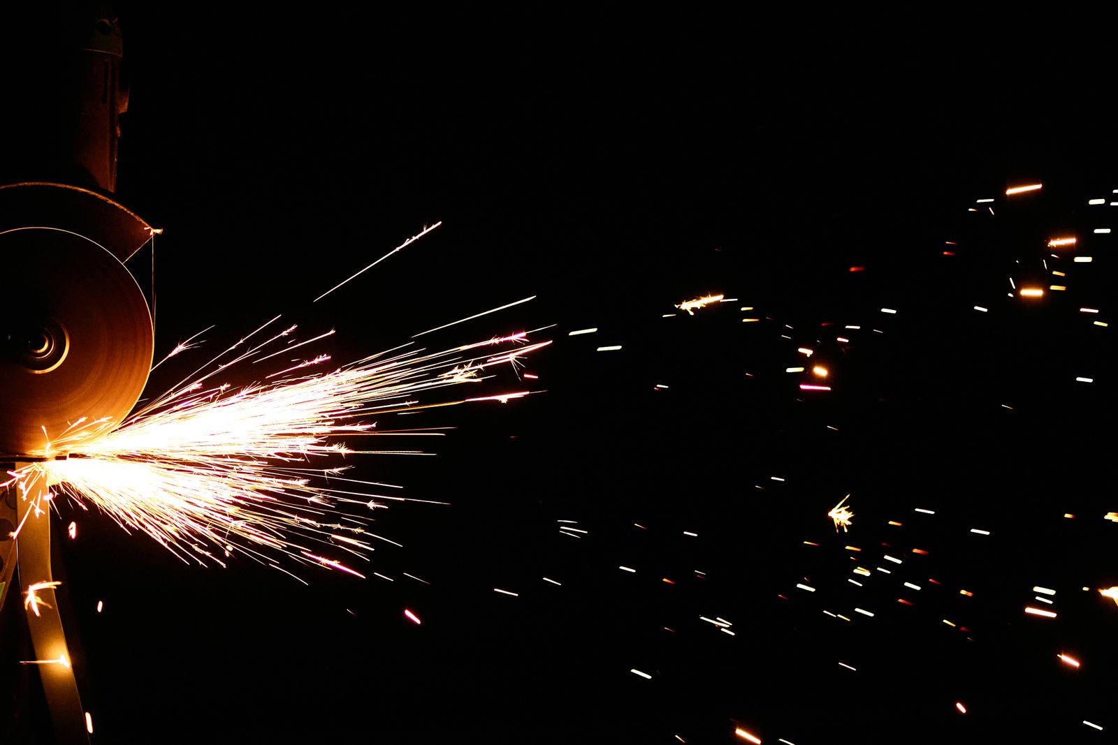 Sparks fly from an angle grinder in a dark fabrication shop
