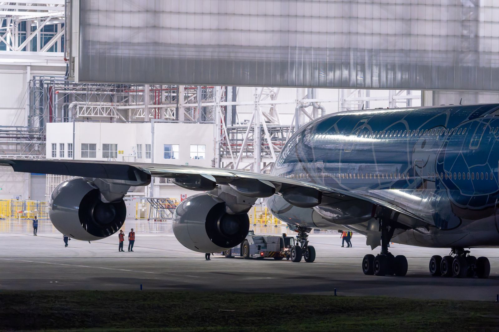 Technicians work around a large airplane in a hangar