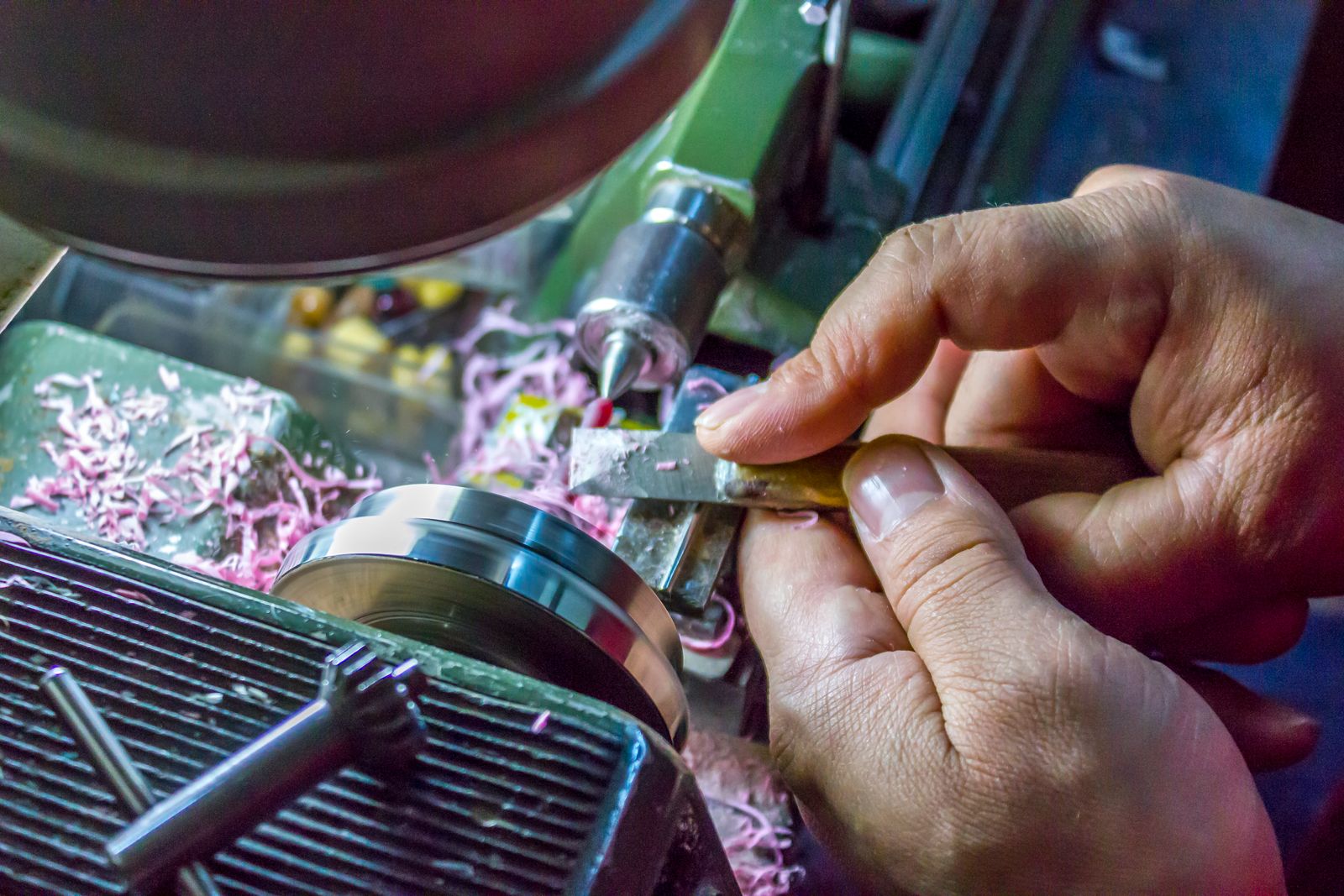 Hands operating a metal lathe