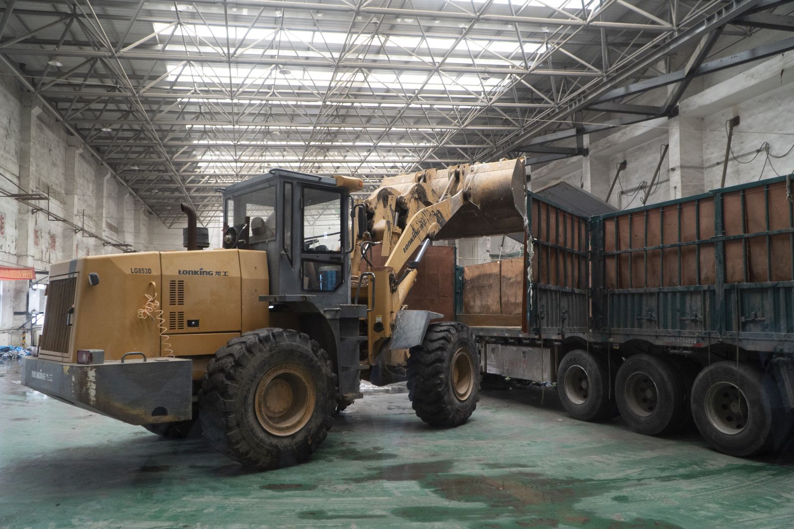 A loader moves materials onto a truck inside a warehouse