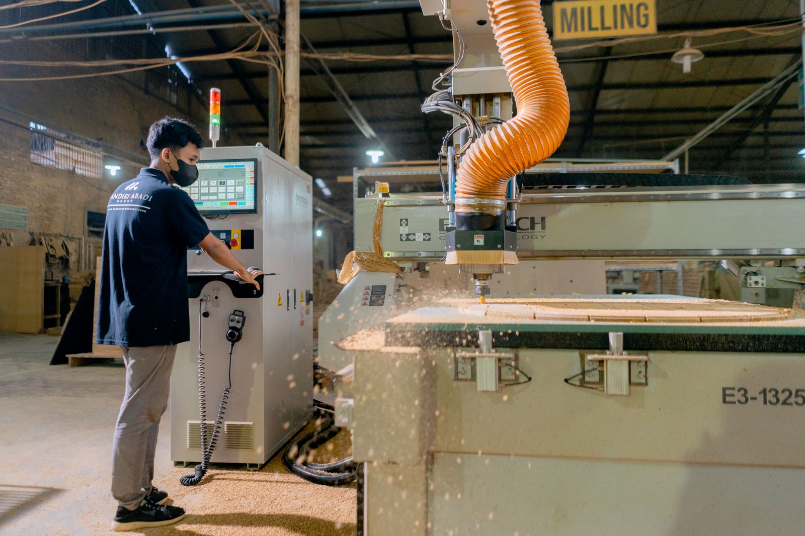 An industrial worker oversees a milling machine