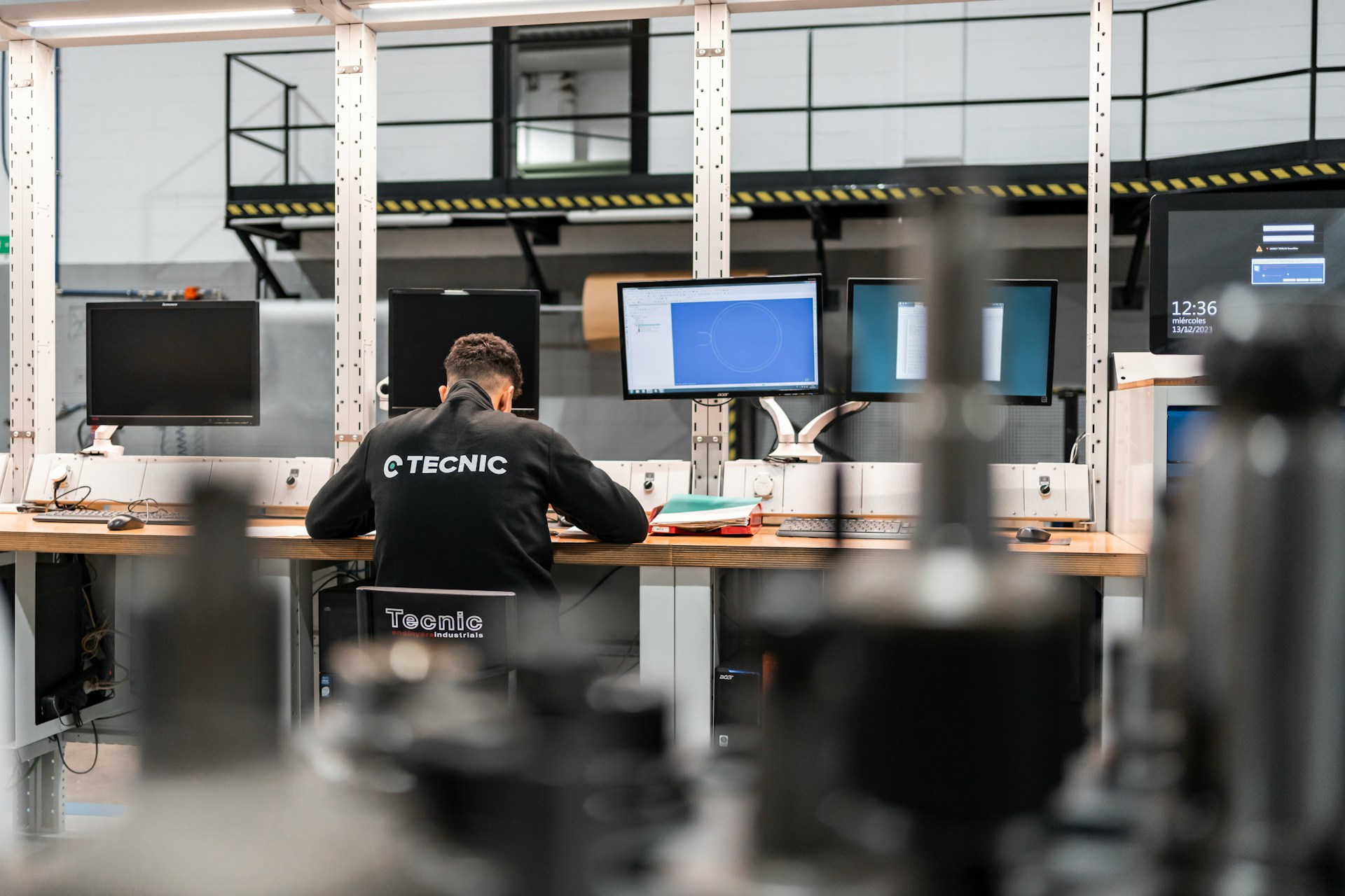 An engineer works at a CAD workstation on a manufacturing floor
