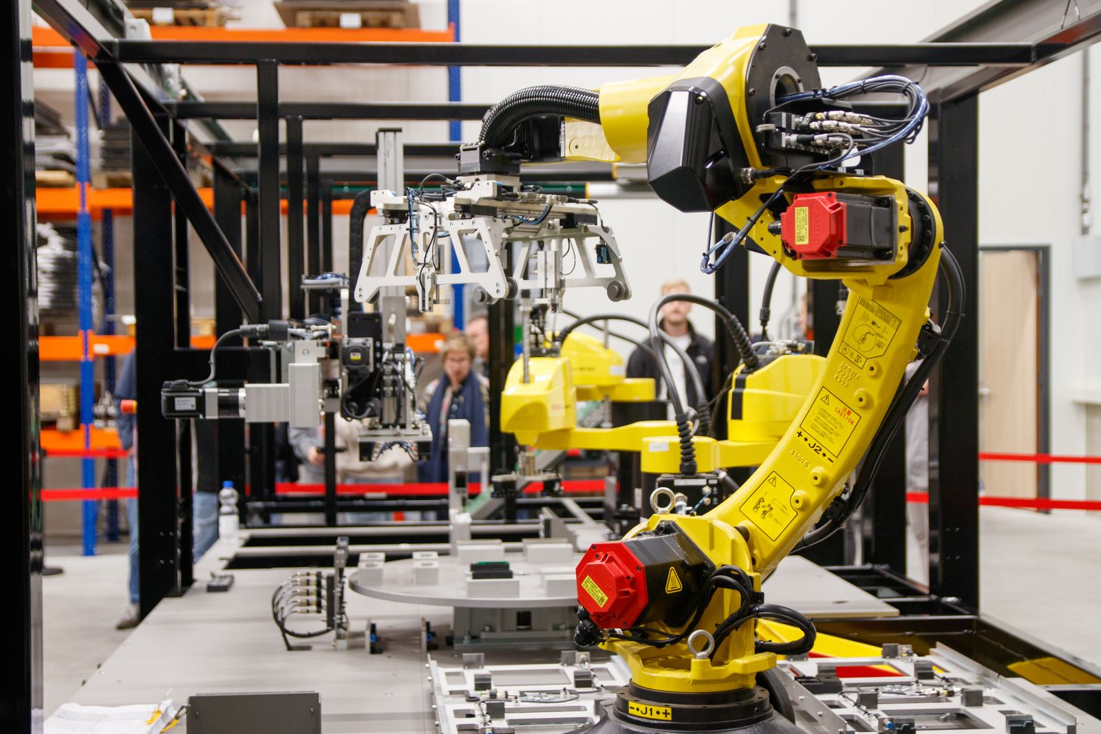 A yellow industrial robotic arm on a manufacturing line