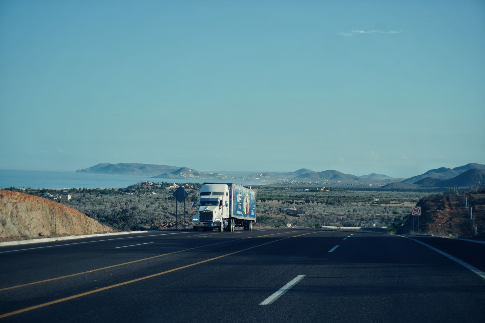 A semi truck on an open highway with mountains behind