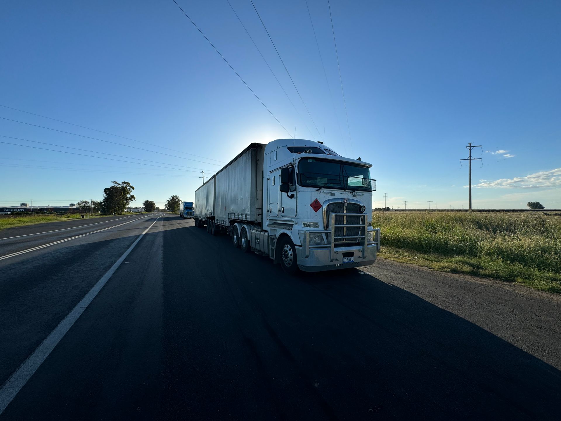 A silver semi truck on an open highway under a clear sky