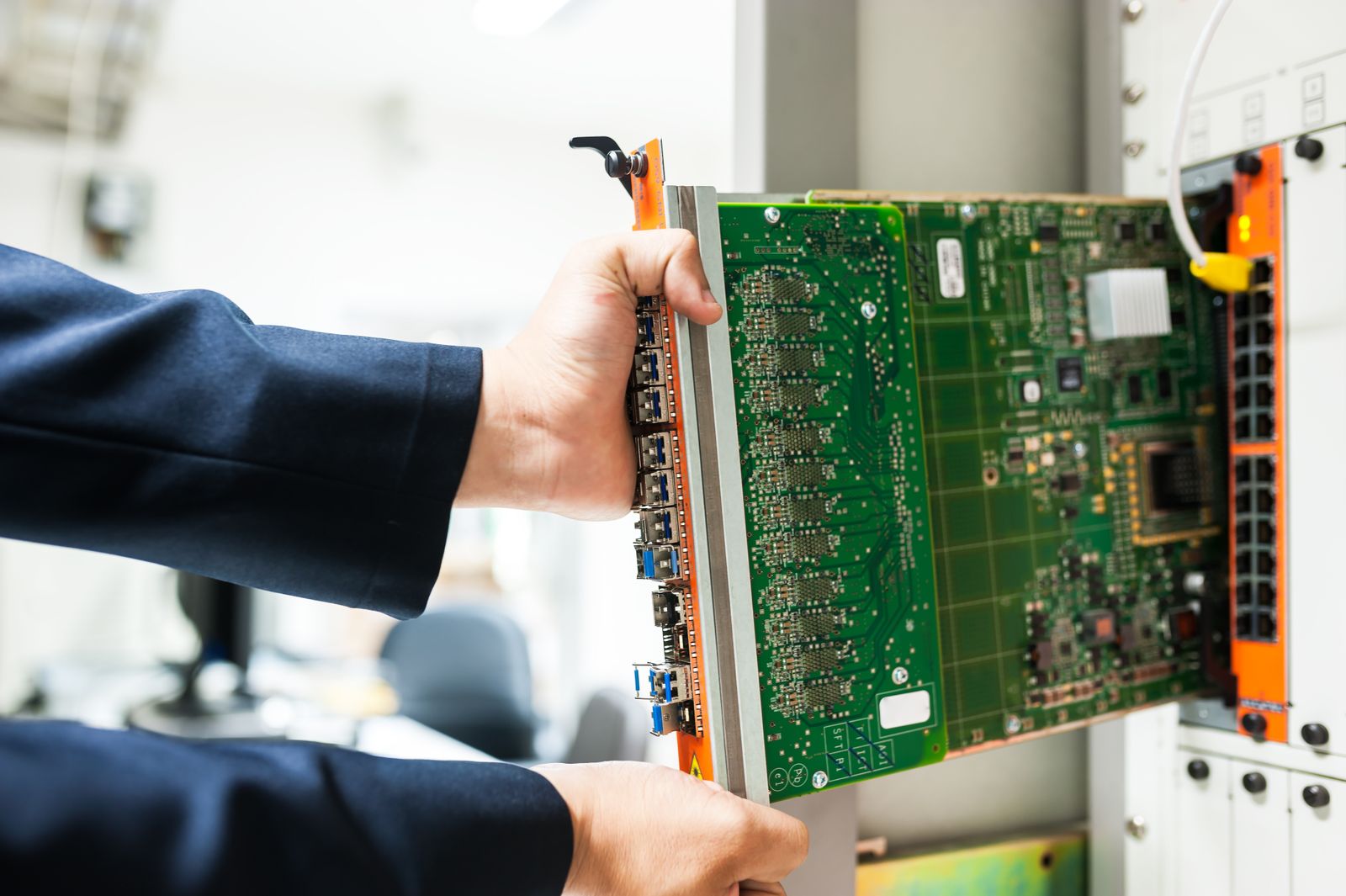 A technician inserts a circuit board into a server rack