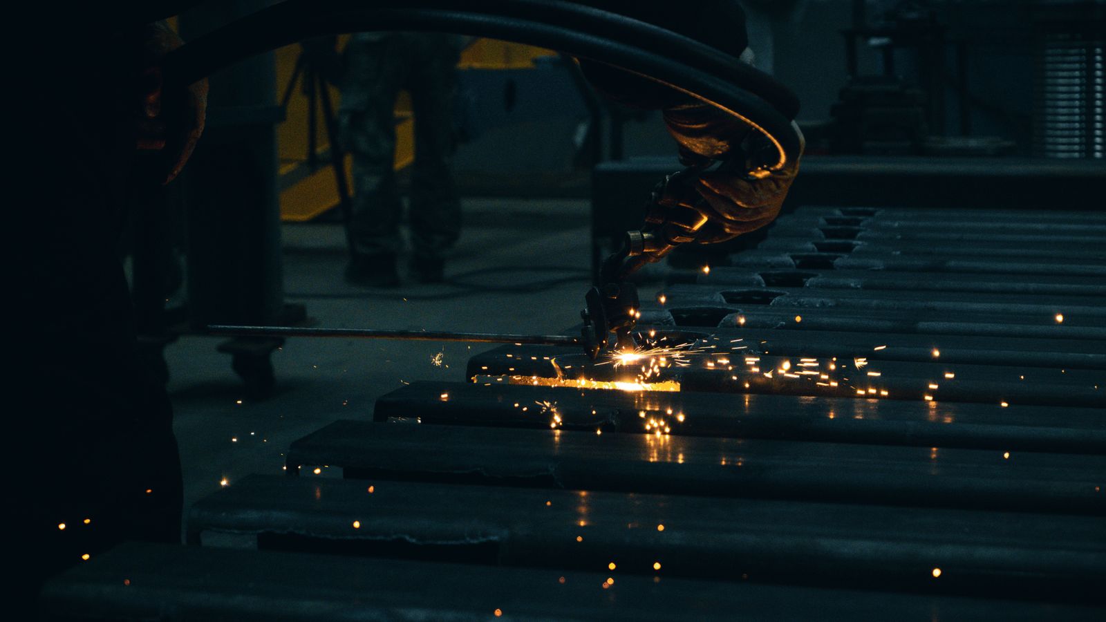 A worker cuts steel as sparks fly