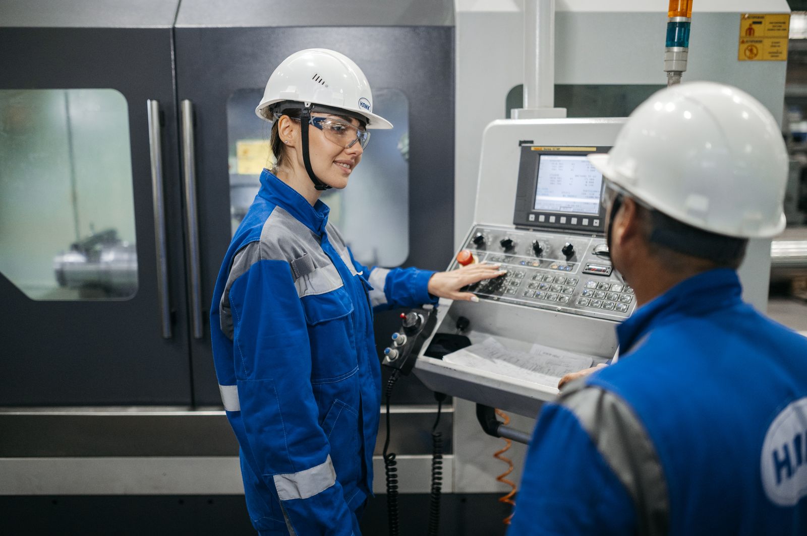 Two industrial workers operate a machine