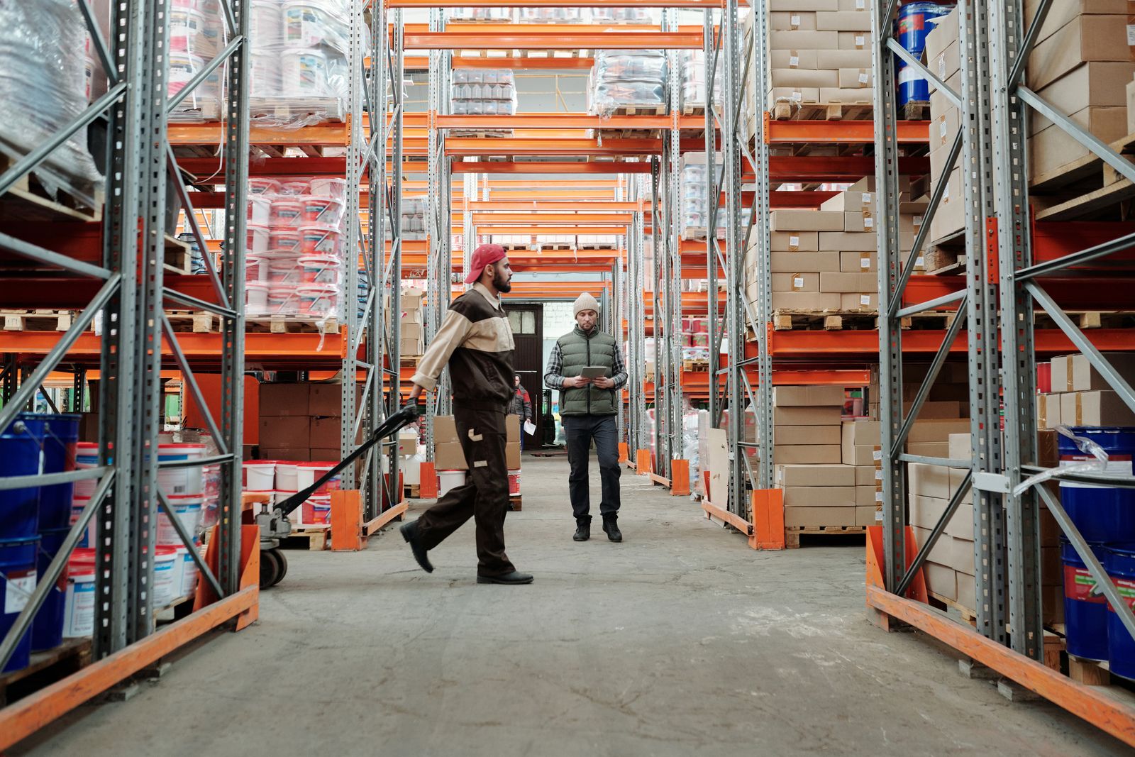 Two workers manage inventory in a warehouse aisle
