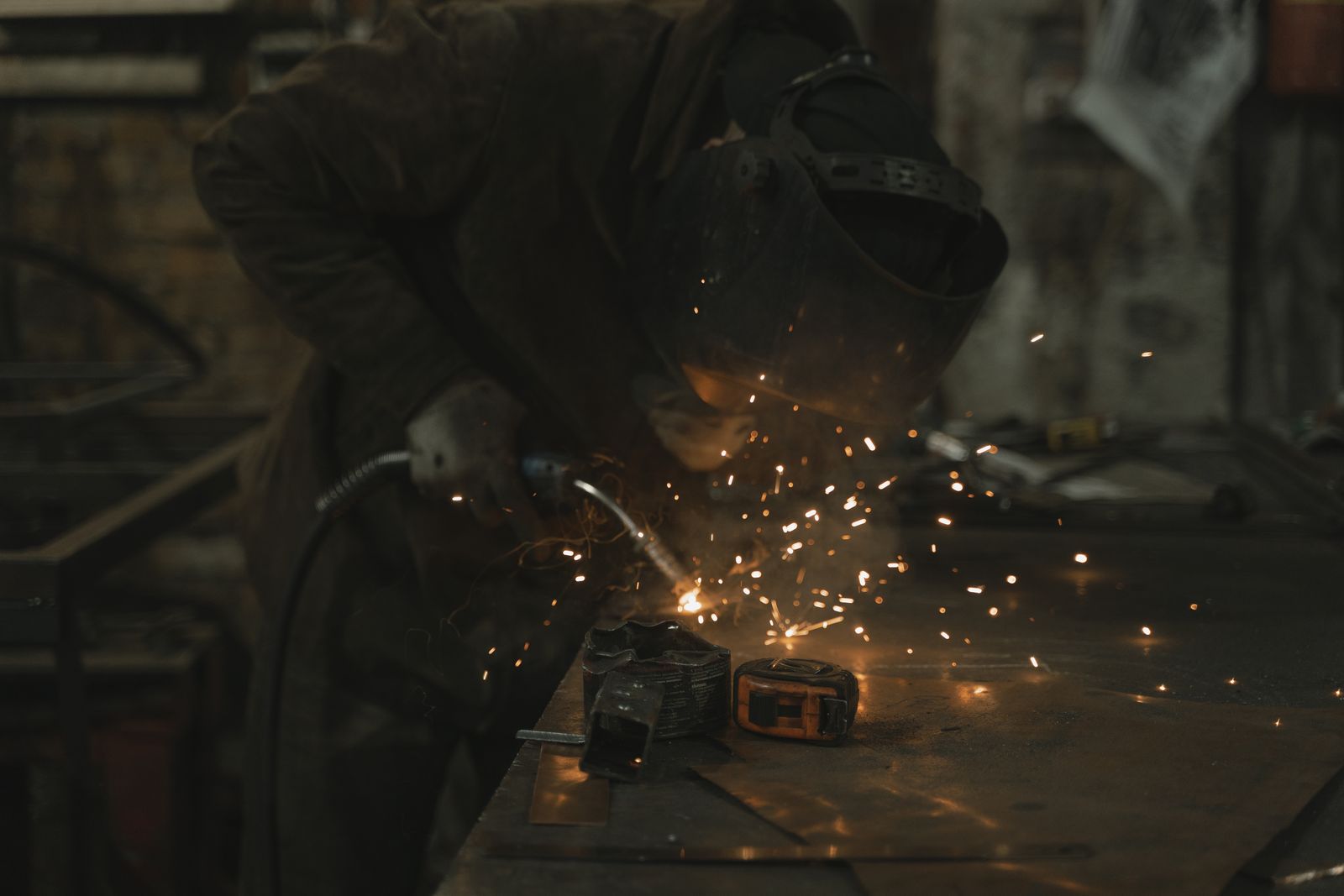 A welder at work in a dimly lit workshop