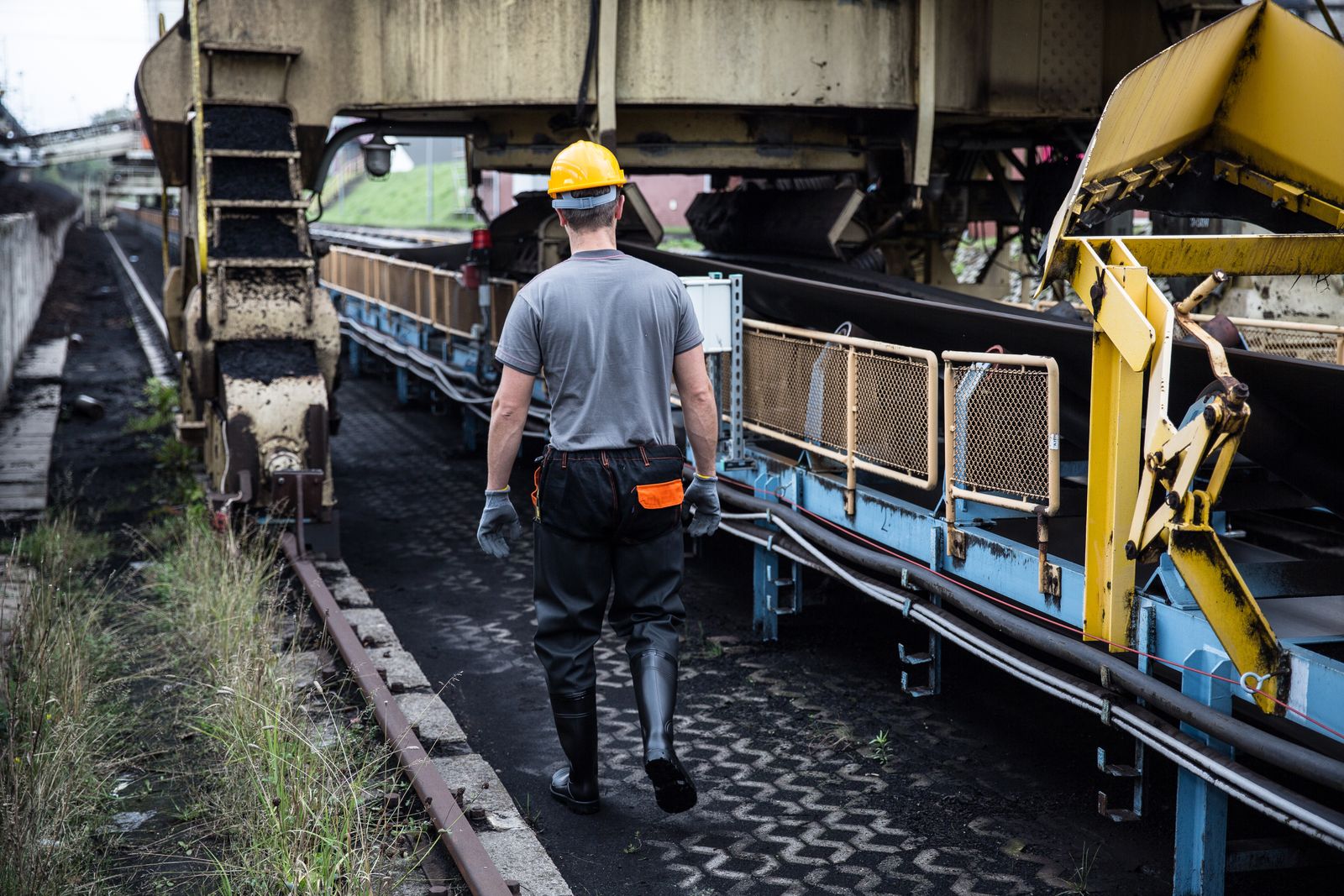 A worker in safety gear examines industrial machinery