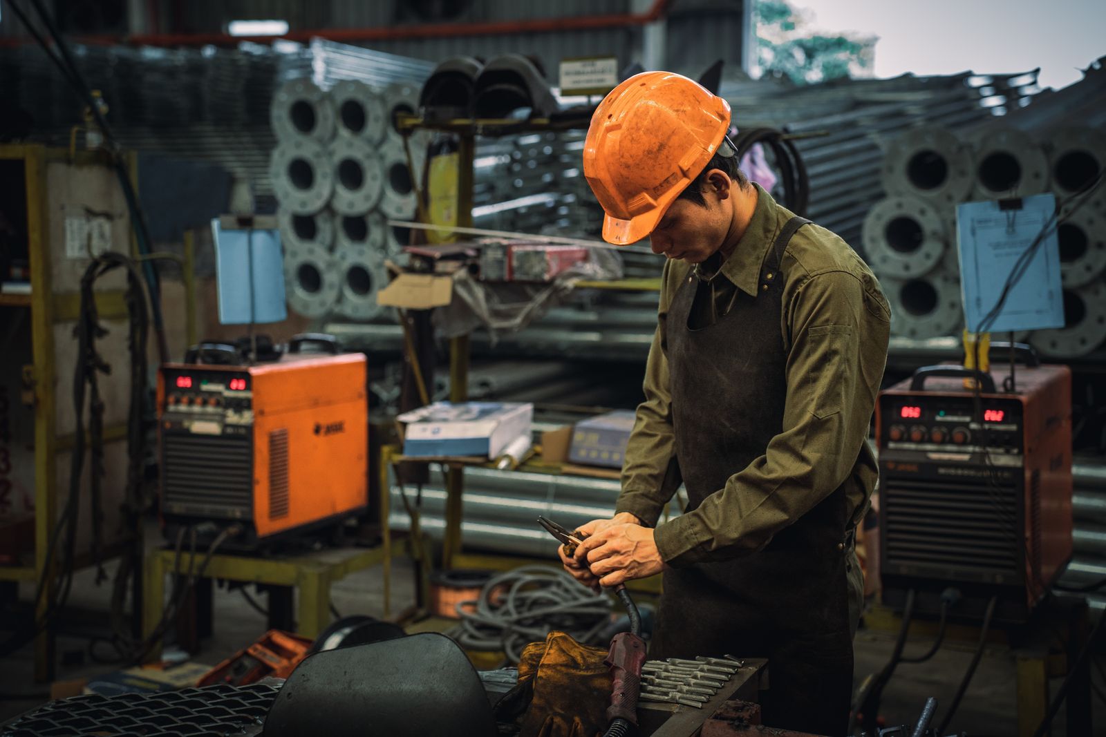 A factory worker in safety gear operates machinery