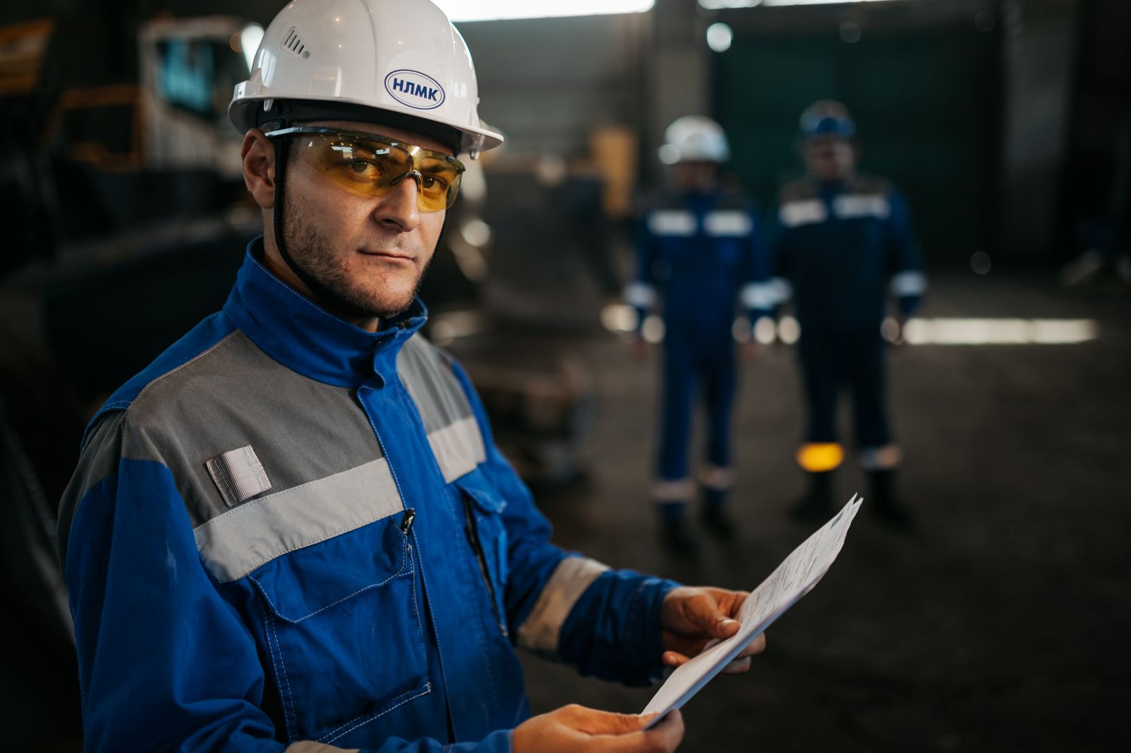 An industrial worker in protective gear reviews documents